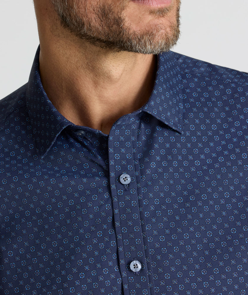 Model is wearing UNTUCKit Performance Short-Sleeve Vandelay Shirt in Navy Medallion Print.