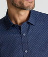 Model is wearing UNTUCKit Performance Short-Sleeve Vandelay Shirt in Navy Medallion Print.
