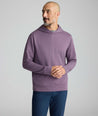 A man wearing a heathered purple long-sleeve hoodie and navy blue pants, standing against a light gray studio background.