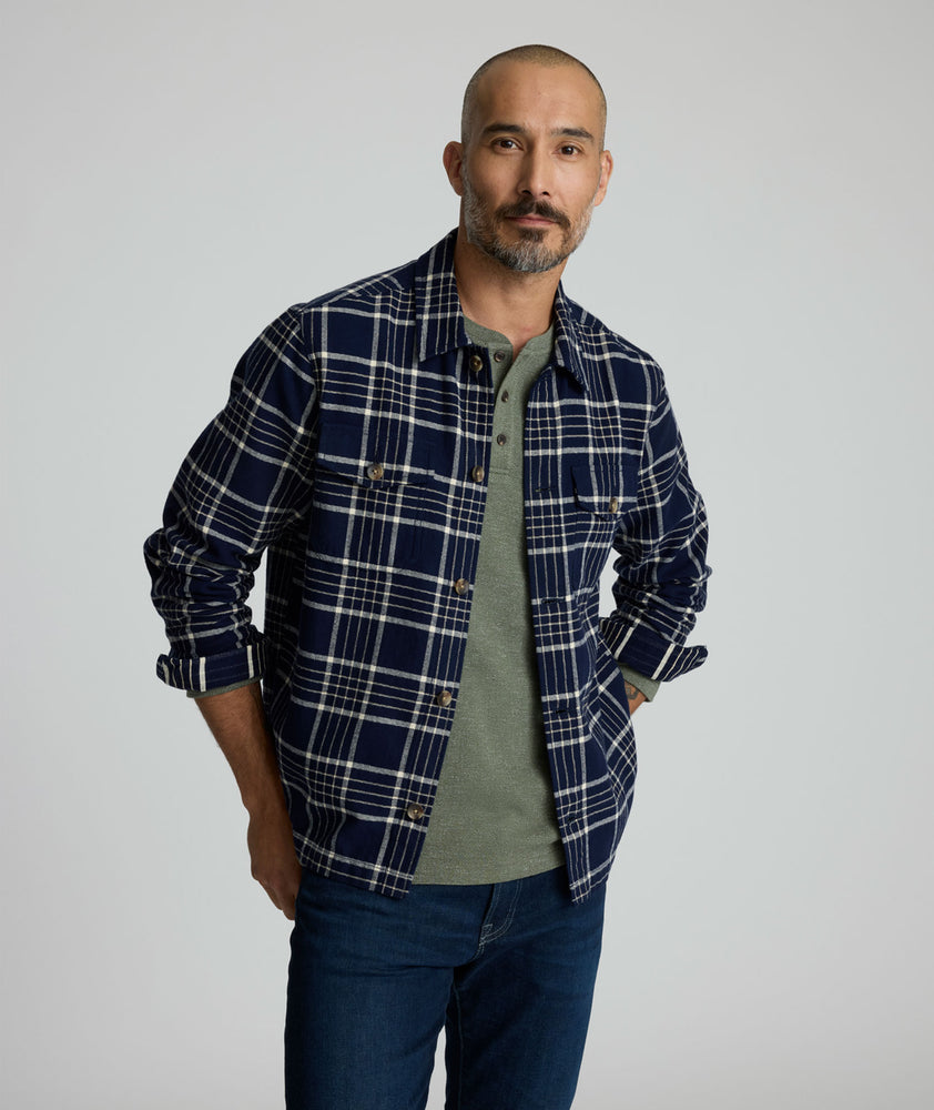 Model is wearing UNTUCKit Whitaker plaid over shirt in navy. 