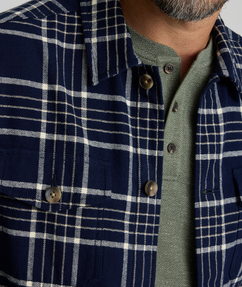 Model is wearing UNTUCKit Whitaker plaid over shirt in navy. 