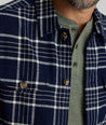 Model is wearing UNTUCKit Whitaker plaid over shirt in navy. 