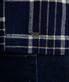 Model is wearing UNTUCKit Whitaker plaid over shirt in navy. 